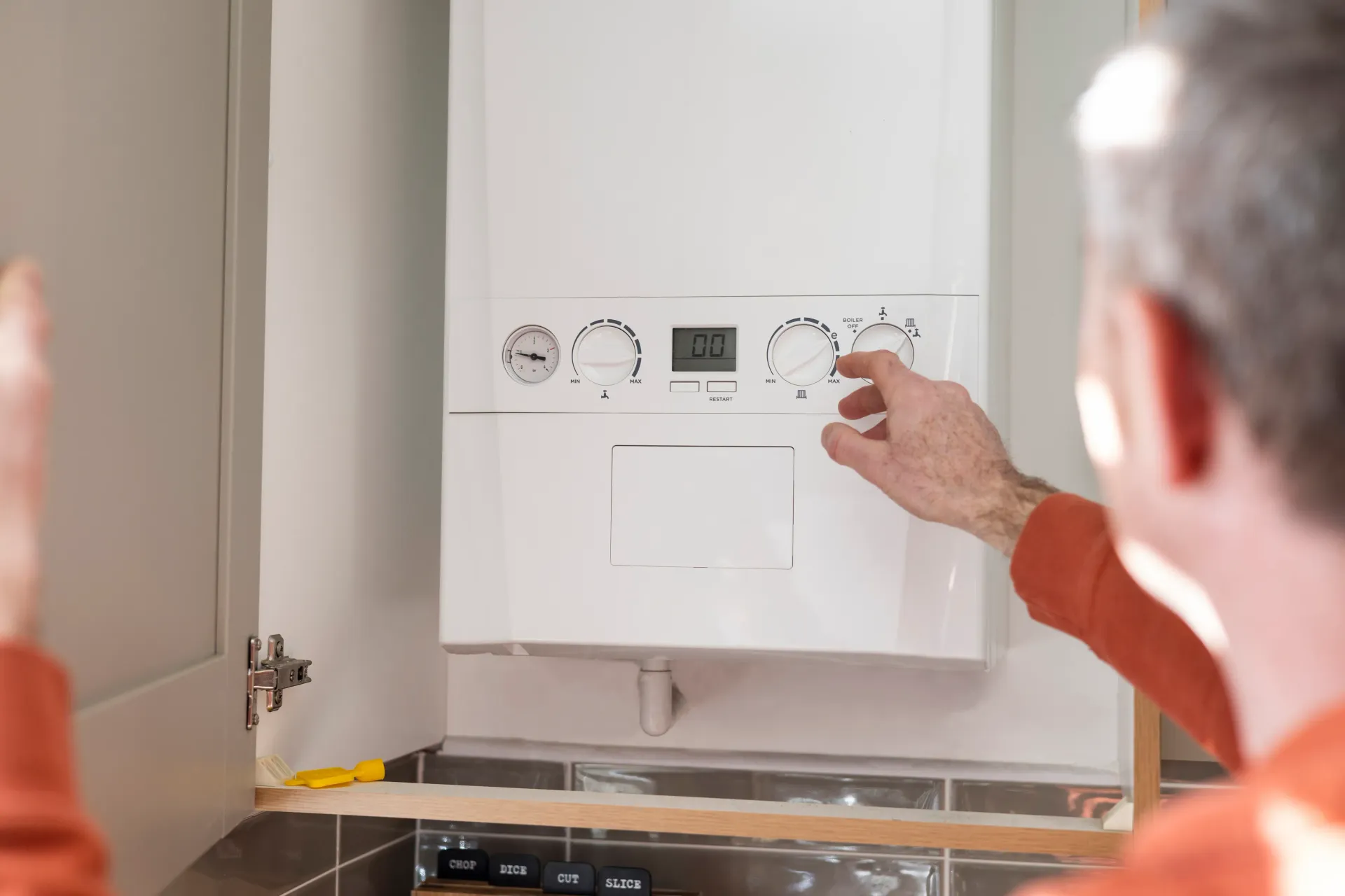 Engineer checking and adjusting a gas boiler during servicing in a UK home